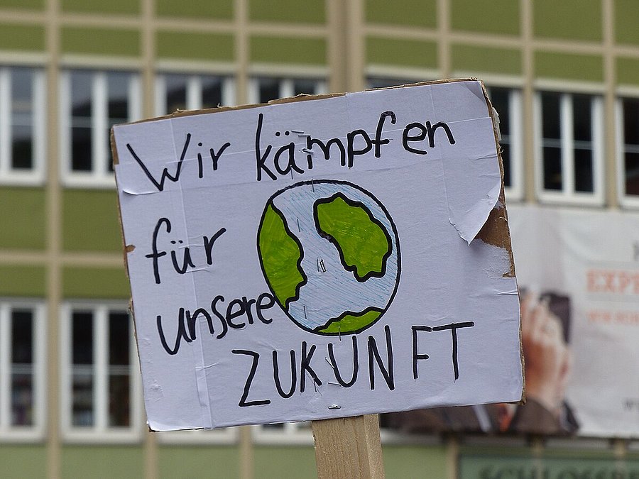 Ein Demoplakat auf dem steht "Wir kämpfen für unsere ZUKUNFT" und eine Erde skizziert ist.