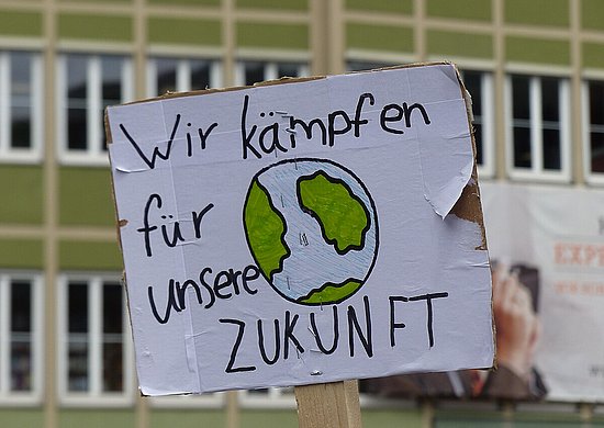Ein Demoplakat auf dem steht "Wir kämpfen für unsere ZUKUNFT" und eine Erde skizziert ist.